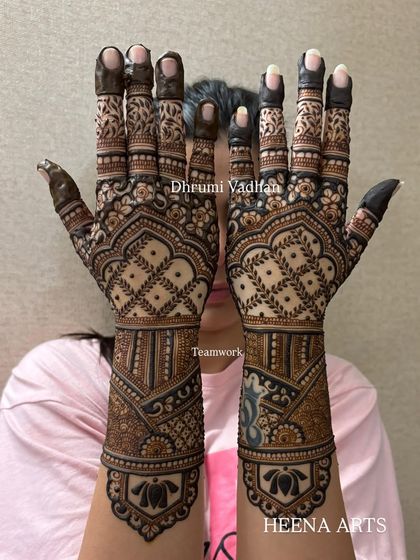 A stunning engagement mehendi for the bride. The design features dense, intricate patterns with leafy vines on the fingers and a beautiful lotus motif on the wrist.