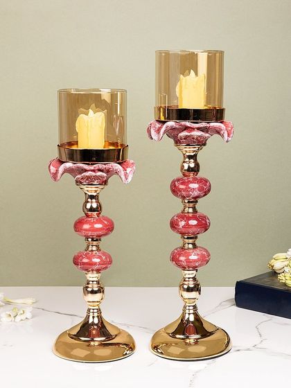 These elegant candle stands feature a beautiful combination of pink ceramic orbs and gold metal. The glass hurricane shade protects the flame while adding to the sophisticated design.