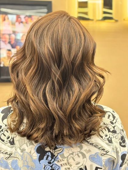 The back of a client's hair after a cut and color service. The wavy style shows off the dimension and shine of the new, vibrant color.