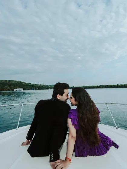 An intimate moment on the bow of a yacht, with the water and shoreline in the background. This shot captures the feeling of a private, luxurious escape.