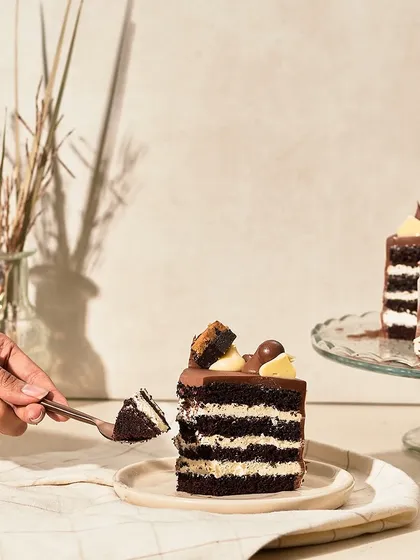This is my Cookie Brownie Chocolate Cake. It features layers of dark chocolate sponge, white chocolate buttercream, and ganache, all topped with pieces of cookie and brownie.