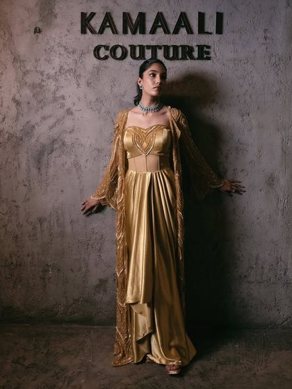 A timeless symphony of structure and sparkle. This corset gown in a rich gold hue features a sculpted sweetheart bodice and is paired with a meticulously hand-embellished jacket.