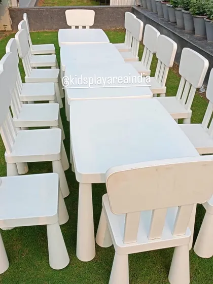 A clean, close-up shot of our sturdy and stylish white kids' tables and chairs arranged on a lawn, ready for a party. This highlights the quality and design of our rental furniture.