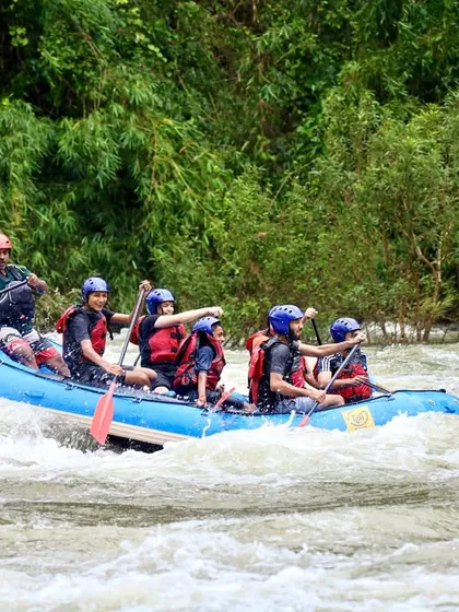 A full raft of participants, guided by our instructor, powers through a wave. This image showcases the dynamic nature of white-water rafting during the monsoon season in Coorg.