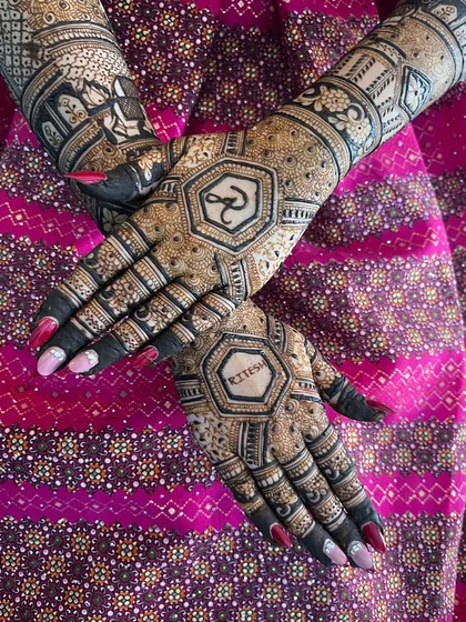 A crossed-hands pose, highlighting the intricate patterns of the back-hand mehendi.