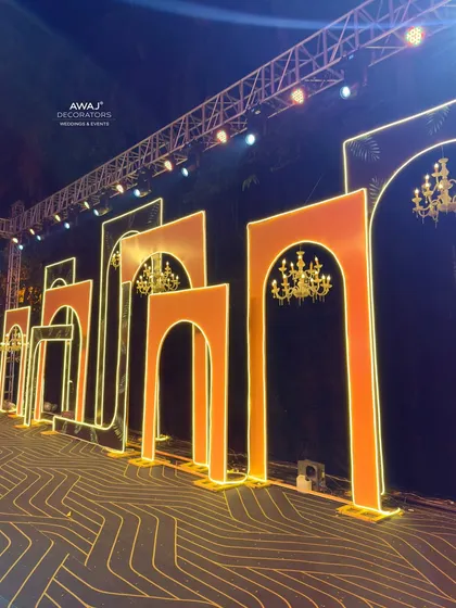 A side view of the Sangeet stage, showing the depth and layering of the illuminated arch structures.
