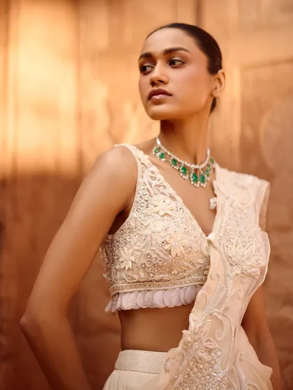 A close-up of the delicate floral embroidery on this ivory blouse from the Awigna campaign shoot. The emerald necklace adds a perfect pop of color.