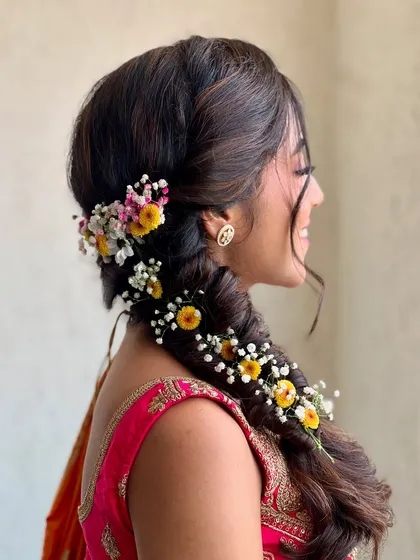 A detailed shot of the intricate fishtail braid adorned with fresh baby's breath and yellow flowers.