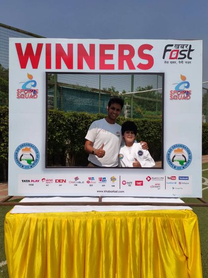 A proud coach and student pose for a photo in the winner's frame.