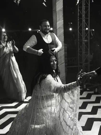 A black and white photo of the bride dancing, capturing a moment of joy and interaction on the dance floor.