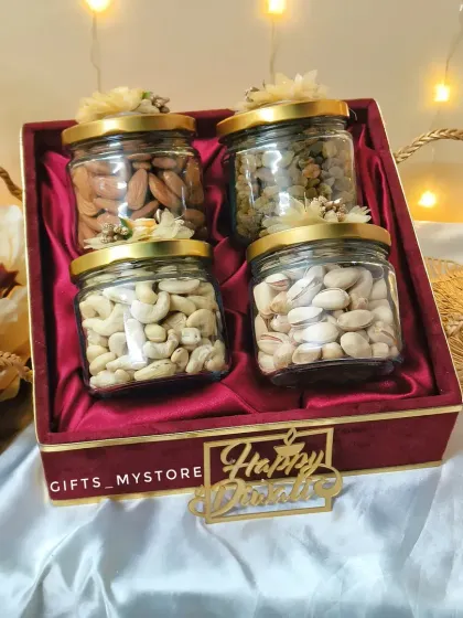 A look inside our red velvet box, showcasing four glass jars filled with premium almonds, cashews, pistachios, and raisins. The simple, high-quality presentation makes this a very popular choice.