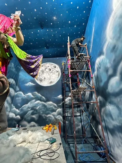 A behind-the-scenes look at the work in progress. You can see me on the scaffolding, adding details to the night sky as the grand Ganpati murti is being set up. It's a race against time, but the energy is amazing.