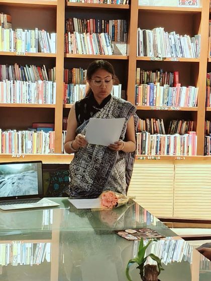 A speaker presenting at a book club meeting, surrounded by the warm wooden shelves of our library. This is the cozy, intellectual heart of our space.