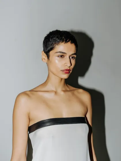 A quiet portrait of a model backstage. The direct, hard light creates a strong shadow, adding a graphic quality to this behind-the-scenes shot.