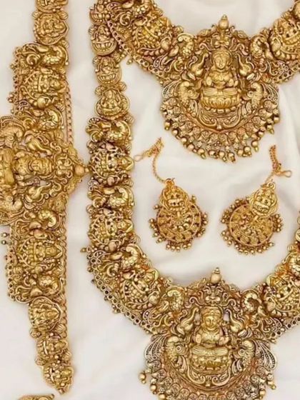 A full antique gold temple jewellery set, including a choker, haram, armlet (vanki), and earrings.