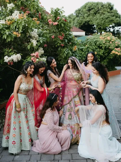 The bride shares a beautiful, candid moment with her bridesmaids in a garden setting, their interactions full of warmth and friendship, showcasing the importance of loved ones.