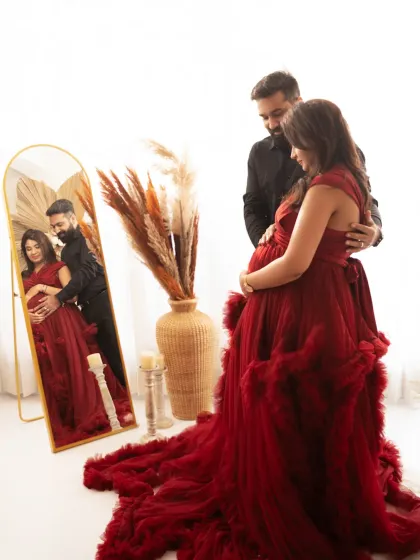 Using mirrors adds a layer of depth and reflection to your portraits. This creative shot in a flowing red gown captures both the expecting mother and her beautiful reflection, creating an elegant and thoughtful image.
