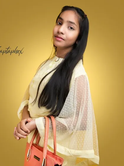 A chic youth portrait featuring a young model with a handbag. The soft lighting and gentle pose create a sophisticated yet age-appropriate look against a warm gold background.