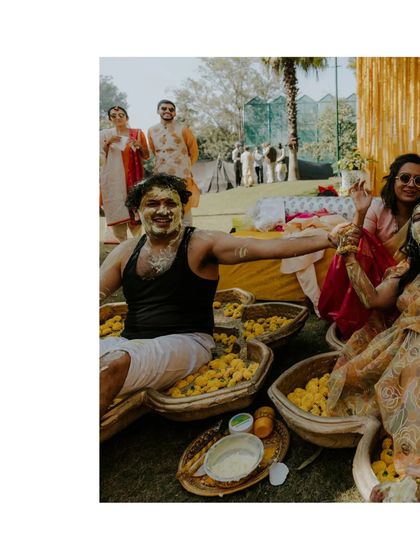 A groom sits in a large vessel of marigolds, laughing as he's covered in turmeric by his loved ones. This is a classic, fun-filled Haldi moment.