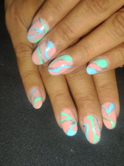 Abstract art for your nails. This design features a playful mix of pastel pink, blue, and mint green with shimmering silver glitter swirls.