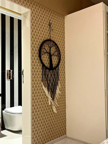 A glimpse into a bedroom where patterned wallpaper and a dreamcatcher add personal touches. The adjoining bathroom features bold, striped tiles, showing how I carry a design theme through different spaces.