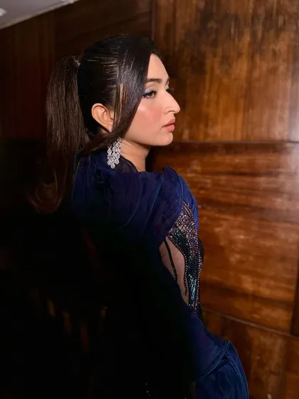 The sleek ponytail adds a modern, chic element to this glamorous cocktail look. The makeup is kept sharp and defined to match the hairstyle.