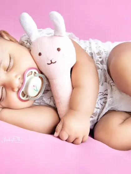 This sleeping angel is cuddling her little bunny, looking so peaceful on a soft pink background. Simple setups like this are perfect for highlighting your baby's natural sweetness.