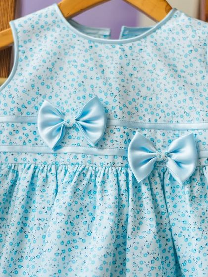 A sweet light blue floral print dress with two perfectly placed satin bows. This simple detail adds so much charm and character to the design.