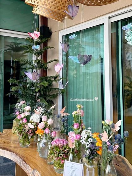 A delicate butterfly-themed baby shower with flowers in glass vases and paper butterflies hanging from the ceiling.