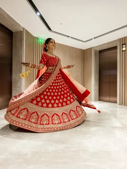 A happy bride twirls in her red wedding lehenga, a classic shot that is full of joy and shows off the beautiful outfit.