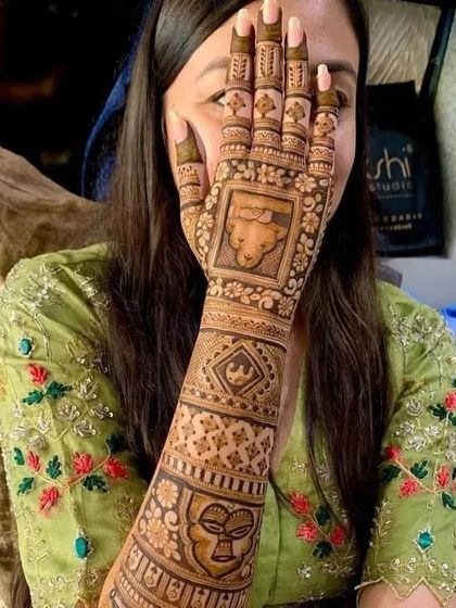 A client showing off her unique mehndi featuring fun, quirky faces and symbols, demonstrating our ability to create any custom design.