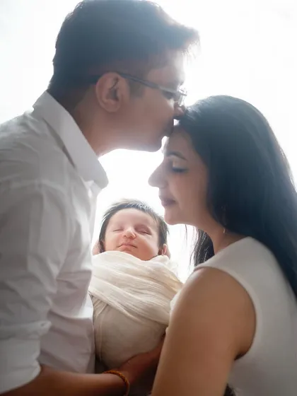 A father's gentle kiss on his wife's forehead as they both hold their newborn. This is a forever kind of feeling, captured in a single frame.