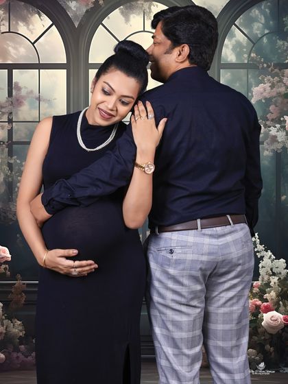 A quiet moment of connection. This moody, romantic portrait shows the mom-to-be resting her head on her partner's shoulder, framed by a soft, floral backdrop.