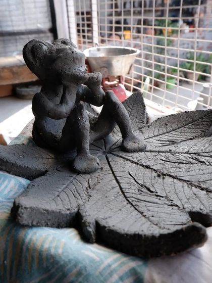 A whimsical sculpture of a figure playing a flute, created by a participant on the first day of a Raku workshop.