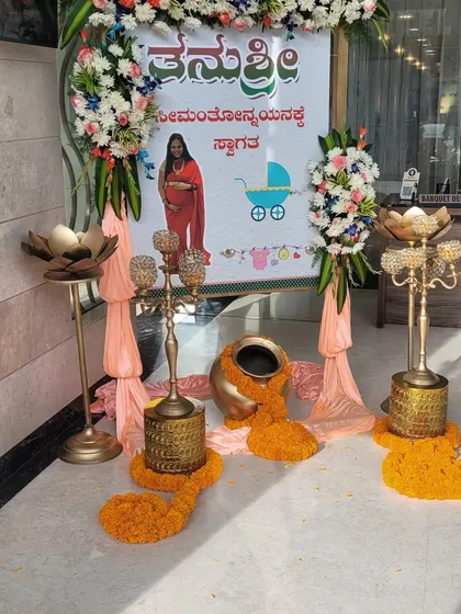 A traditional welcome setup for a baby shower, with a custom banner in Kannada. The decor includes marigold garlands, brass lamps, and a traditional pot (kalasha) for an authentic and auspicious feel.