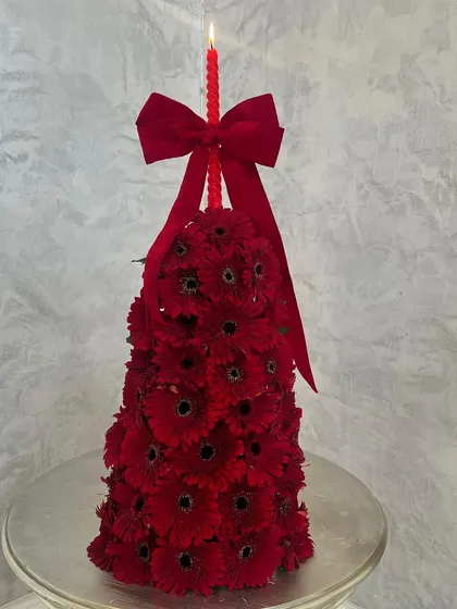 Chic, glorious, and festive. This unique Christmas tree is made entirely of fresh red gerbera daisies, complete with a matching red candle on top. It's a modern and floral take on a holiday classic.