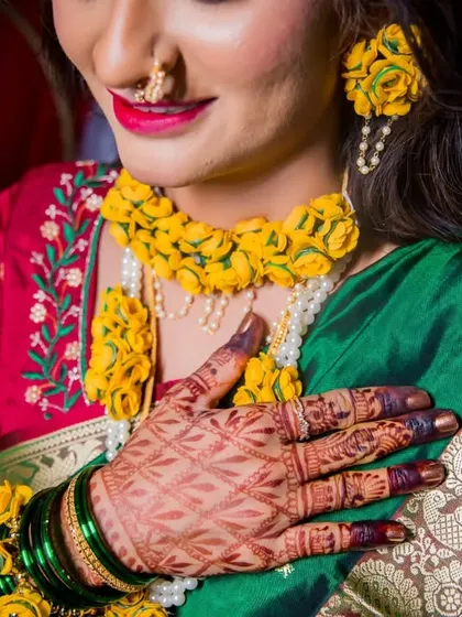 A detailed shot of the bride's Haldi look, focusing on her floral jewelry and the beautiful contrast with her traditional saree.