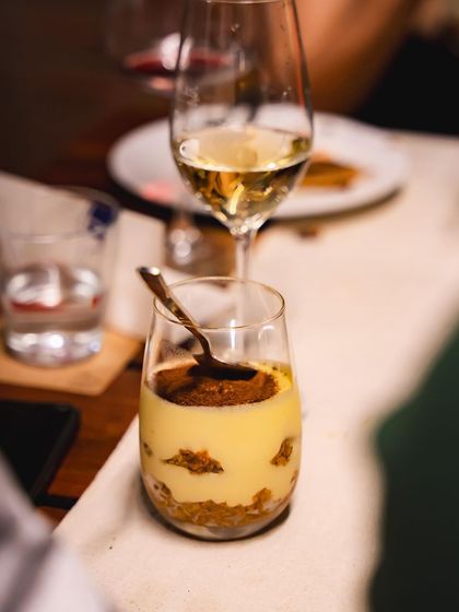 A classic Tiramisu dessert in a glass, served alongside a glass of white wine at our pizza and wine night.