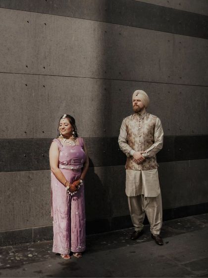 A beautifully composed shot of the couple standing in a sliver of light against a dark, textured wall. The dramatic lighting creates a moody and artistic portrait.