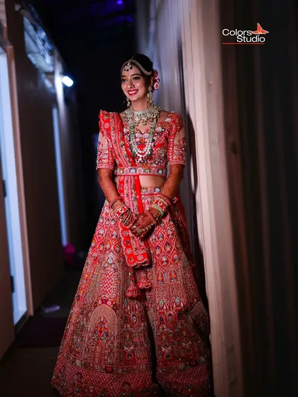 A full-length shot of the bride in her magnificent red wedding lehenga, looking absolutely radiant.