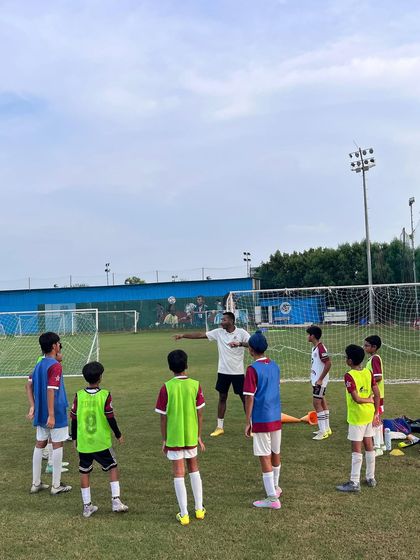A coach giving instructions to a group of young players during a training session. Clear communication is a key part of our coaching method.
