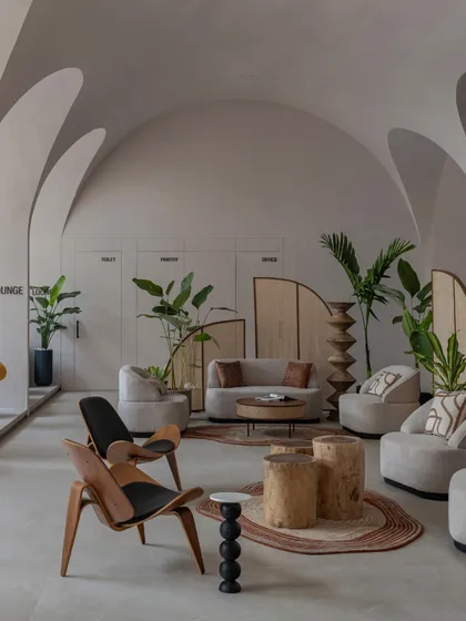 The main seating area is a curated collection of contemporary and classic furniture, including a striking mid-century modern chair that contrasts with the soft, curved sofas.
