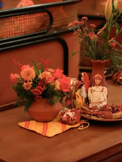Another view of the charming tabletop with traditional dolls and rustic floral arrangements, set on a wooden tray.