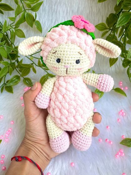 A sweet pink lamb made with a mix of regular and fluffy yarn for a lovely texture. She comes with a removable flower headband.