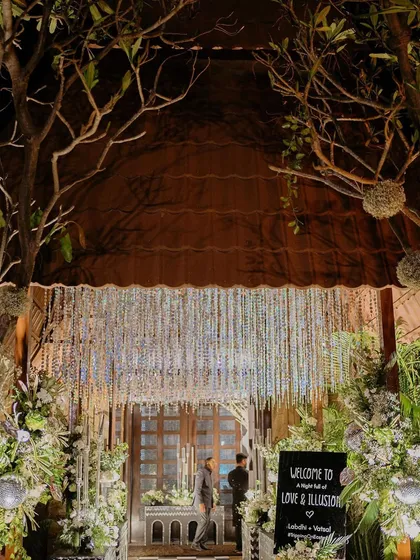The entrance to the 'Love & Illusion' Sangeet, with a dramatic crystal curtain and enchanting tree branches.