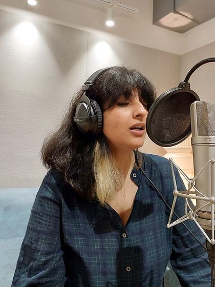 A close-up of Sukhnidh Kaur recording vocals with our Neumann U87 mic. We ensure every artist has access to top-tier equipment.