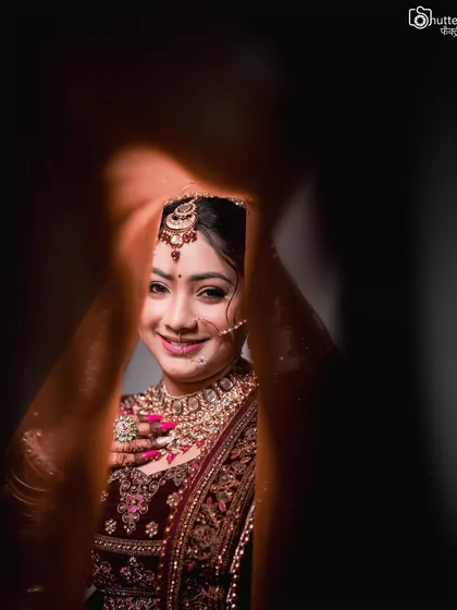 A creative bridal portrait, peeking through a gap to capture the bride's happy smile. We use unique angles and framing to make your portraits stand out.