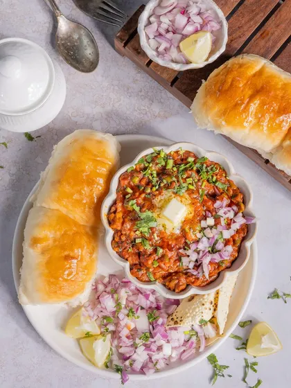 Mumbai's iconic Pav Bhaji, styled to look extra tempting. The dollop of melting butter, finely chopped onions, and soft, buttery pav make this a classic comfort food shot.