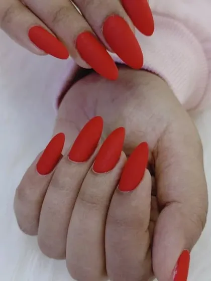 A side view of the long, matte red almond nails, showing their elegant shape.