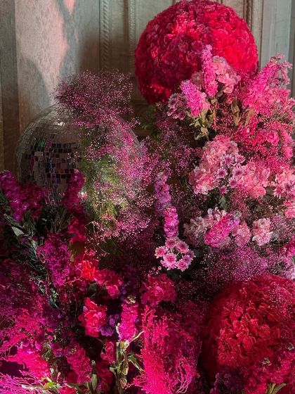A close-up detail of the pink floral arrangements, showing the rich textures and shades, from deep fuchsia to soft blush. A disco ball is cleverly nestled within the blooms, adding a hint of sparkle and fun to the romantic decor.